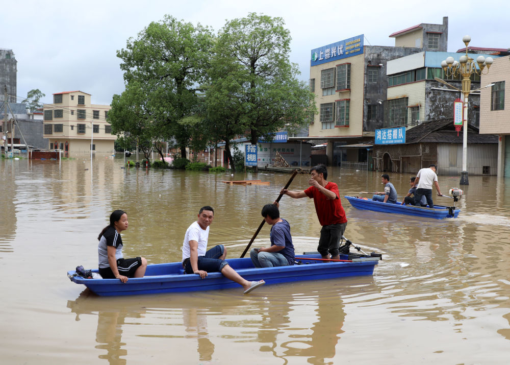4月21日，广东清远英德市浛洸镇居民在积水的道路上乘船出行。新华社记者　黄国保　摄