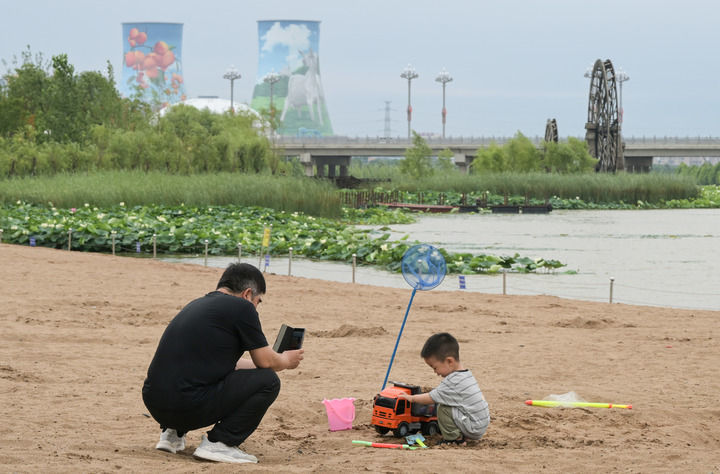 市民在富平石川河国家湿地公园岸边的沙地玩耍（6月21日摄）。新华社记者 李贺 摄