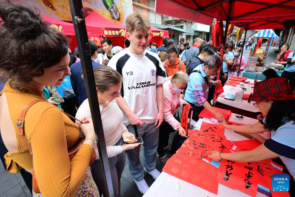 2月4日，香港市民、游客及留学生在香港庙街观看艺术家写书法，庆祝即将到来的春节。图源：新华社