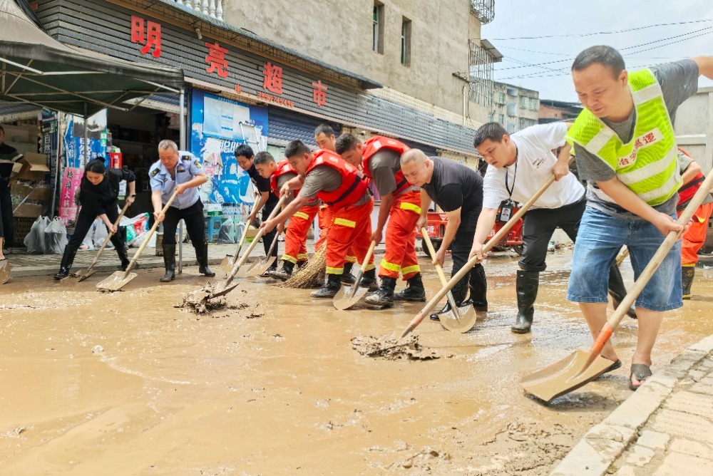 ▲7月12日，垫江县永平镇，志愿者正在忙着清除淤泥、清洗杂物，着手灾后重建。首席记者 龙帆 摄