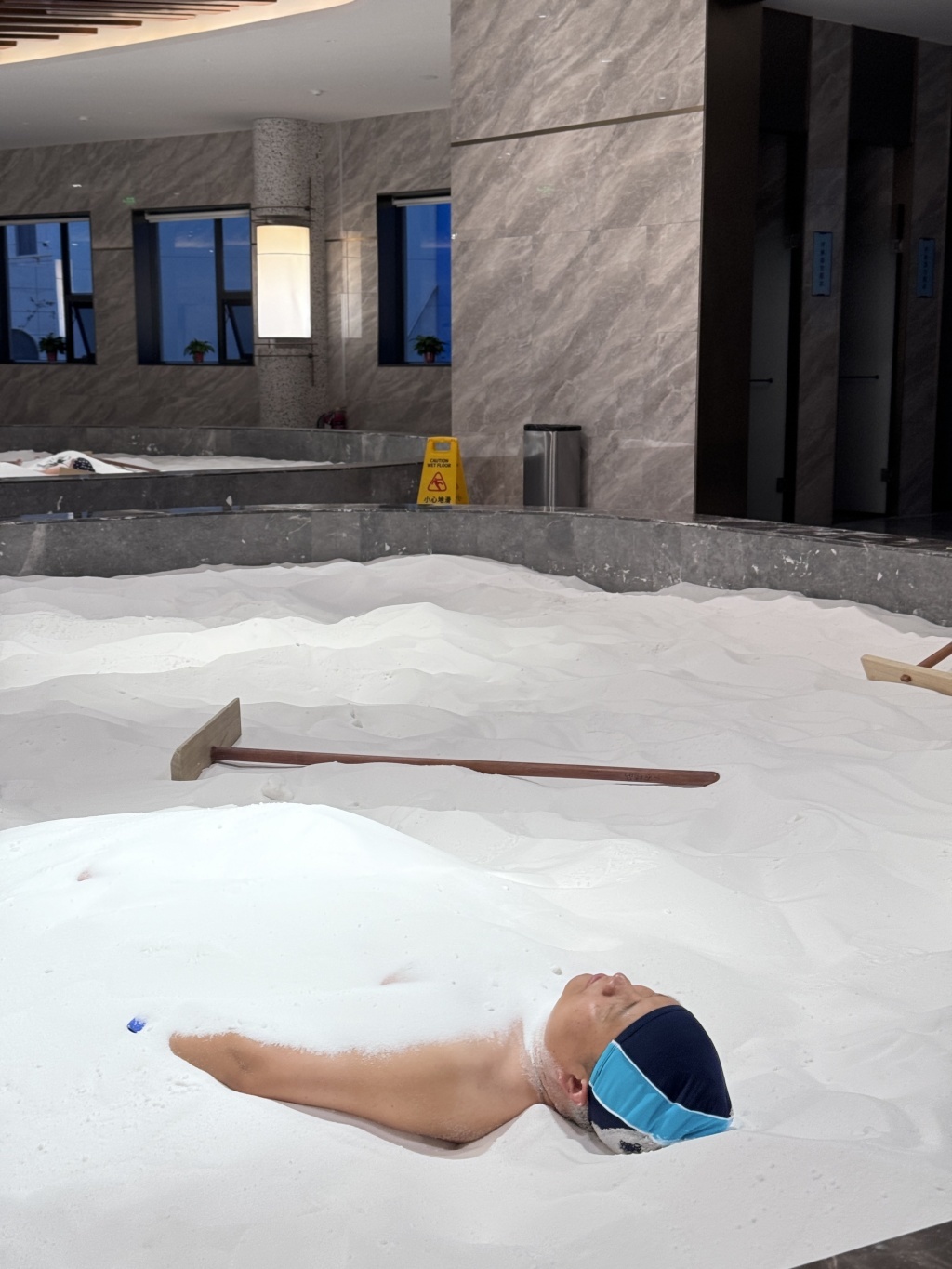 一位游客正在进行矿盐理疗，通过矿盐覆盖全身以达到促进血液循环、疏通经络的作用。 澎湃新闻记者 金向玉 摄