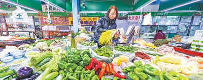 北京朝阳区,社区菜市场内蔬菜瓜果等产品品种丰富,供应充足。图为摊主在整理蔬菜摊位。本报记者 蒋雨师摄