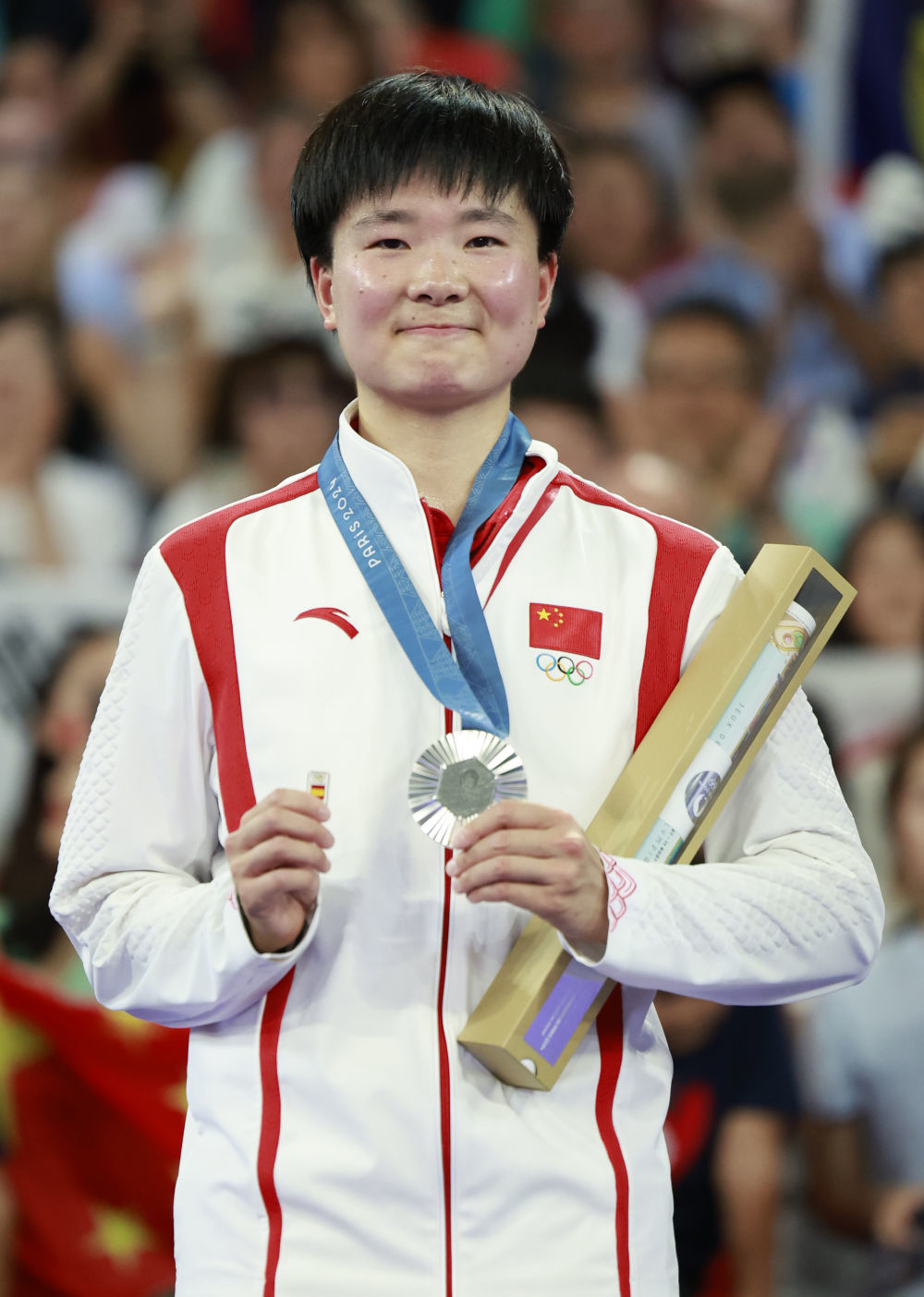 ↑8月5日,在羽毛球女单颁奖仪式上,亚军中国选手何冰娇在颁奖仪式上手持西班牙徽章。她在半决赛中的对手、西班牙人马林因伤退赛,何冰娇晋级决赛。