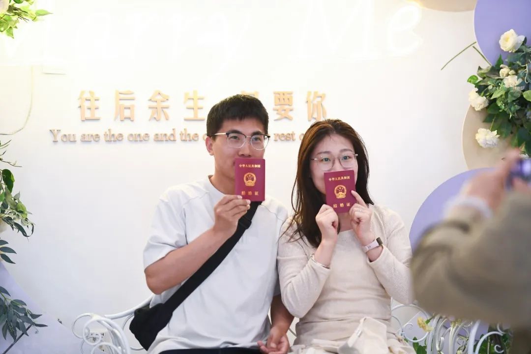 婚姻登记“全国通办”首日 多地新人预约登记结婚。2025年5月10日，手持结婚证的新人在江苏省南京市建邺区民政局婚姻登记处拍照留念。（图/视觉中国）