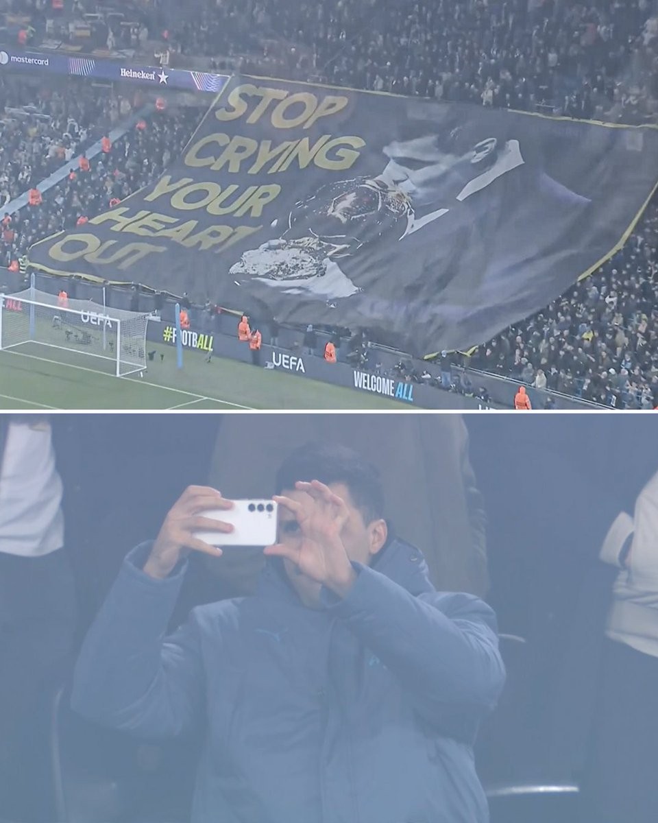 曼城球迷展示罗德里亲吻金球TIFO,罗德里拿起手机拍照记录
