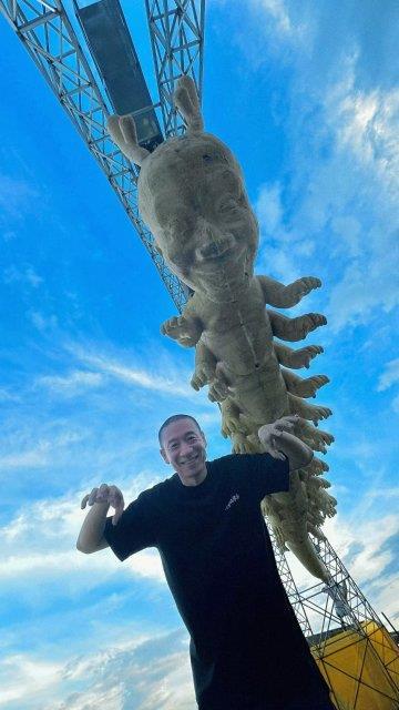 梁龙本人与正在建造中的雕像合影(图源:澎湃新闻)