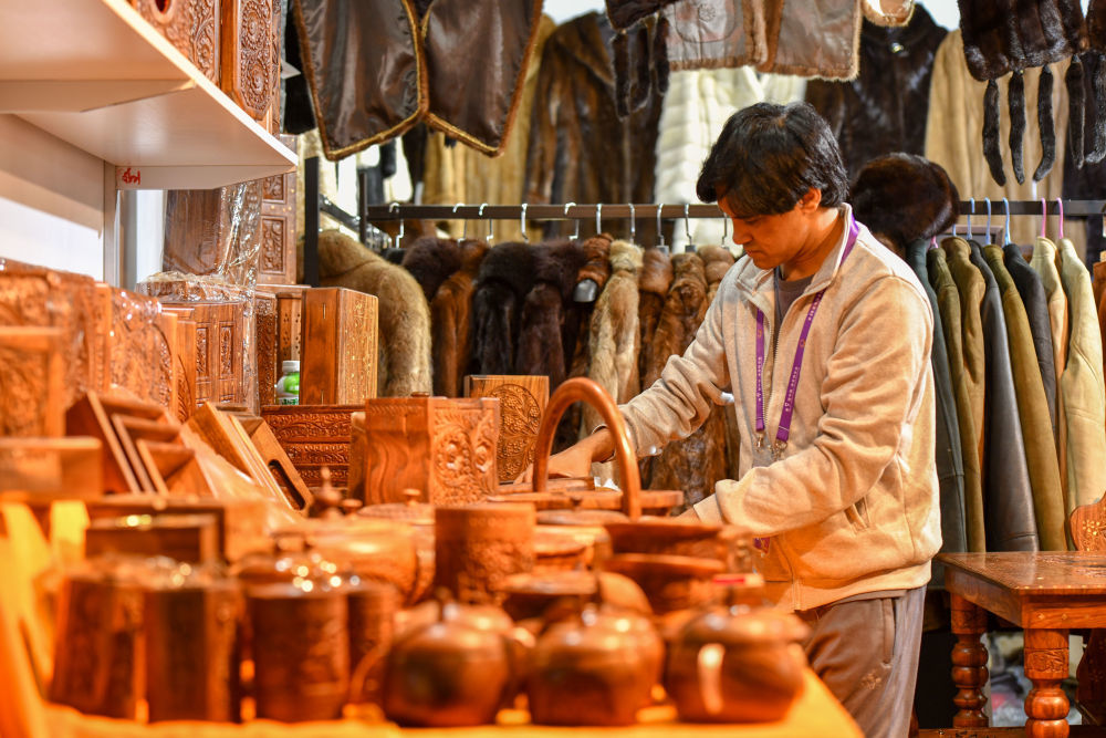 6月21日，一名南亚馆巴基斯坦展区的展商在摆放木制手工艺品。