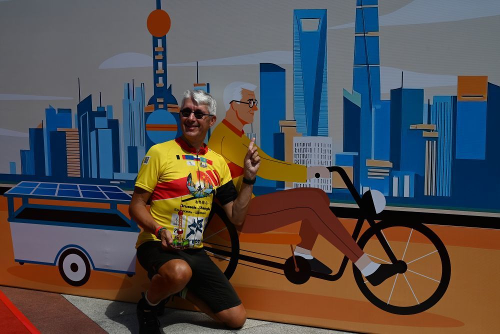 8月30日,在上海东方明珠广播电视塔城市广场,骑行爱好者克劳德·布鲁尔与自己的漫画形象背景墙合影。新华社记者 陈爱平 摄