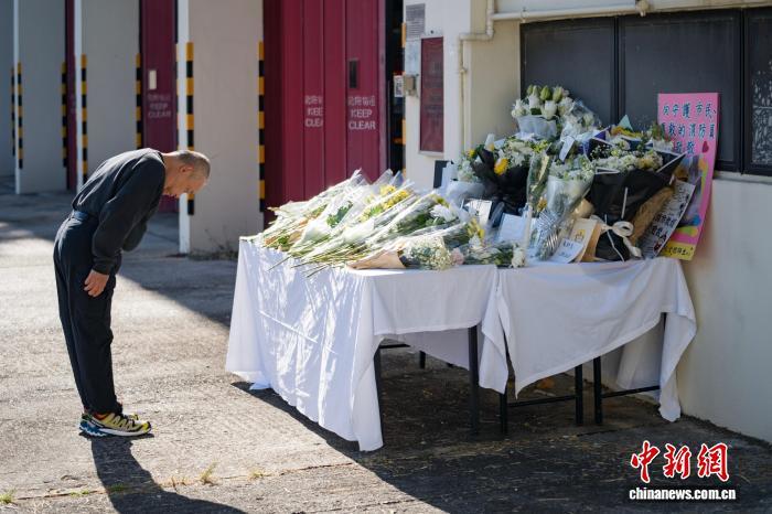 11月29日,香港特区政府消防处沙田消防局外,一位市民向在大埔宏福苑火灾中殉职的消防员何伟豪献花、鞠躬致敬。 中新社记者 侯宇 摄
