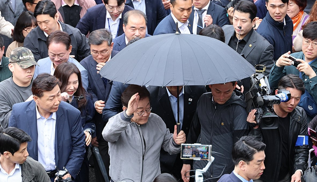 当地时间3日，李在明在江原道束草中央市场参加活动时，安保人员在其周围进行护卫 图源：韩媒报道配图