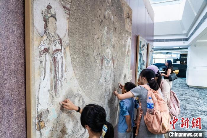 图为家长带小朋友近距离参观莫高窟石窟壁画的复制品　中新网记者　侯宇　摄
