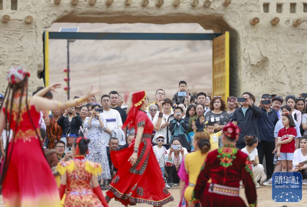 ↑ 5月4日,游客在新疆吐鲁番市鄯善县吐峪沟景区欣赏民族歌舞表演。