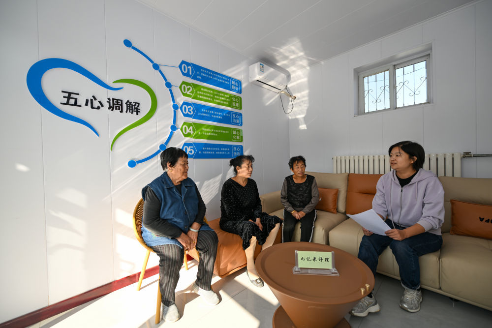 在天津市宁河区芦台街道金华路社区,社区党总支副书记吴蕊(右一)就社区监控设备安装问题为社区居民进行解答(2024年10月11日摄)。金华路社区积极践行新时代“枫桥经验”,将原社区居委会闲置用地提升改造成为联络群众的基层综合治理阵地——“解铃小院”。新华社记者 孙凡越 摄