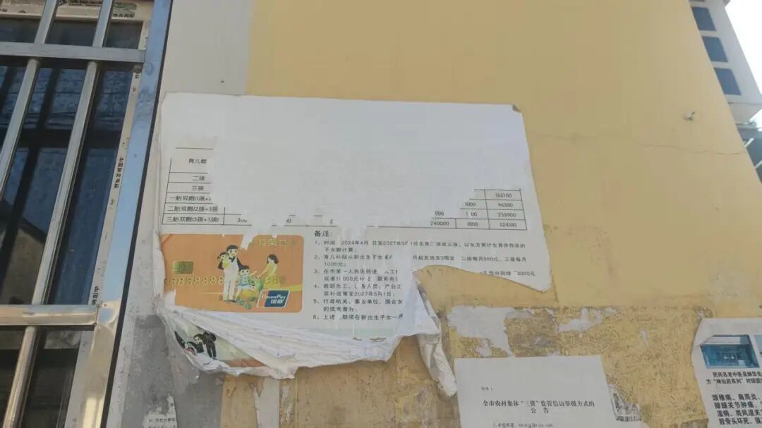 三桥村村委会外墙,破损的宣传海报,发放补贴的银行卡被称为“生育荣誉卡”