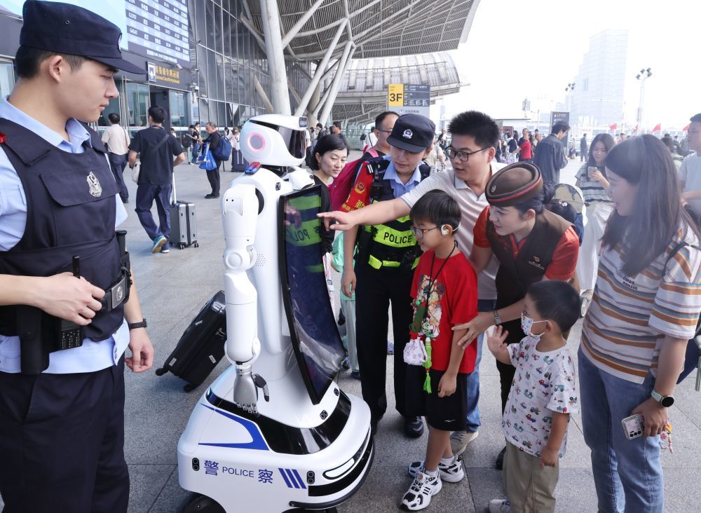10月1日,在湖北省武汉站,小朋友和机器人互动。新华社发(赵军摄)