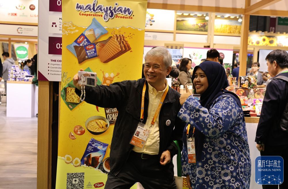 ↑ 11月7日，在第八届进博会农食产品展区，新加坡展商（左）和马来西亚展商合影。新华社记者 方喆 摄