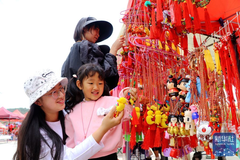 ↑ 5月24日，在甘肃省平凉市静宁县成纪文化城广场，人们在选购香荷包。新华社发（王毅摄）