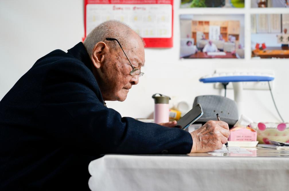 ↑在四川省南充市五福堂颐养院，刘寿山抄录手机上的新闻信息（4月9日摄）。
