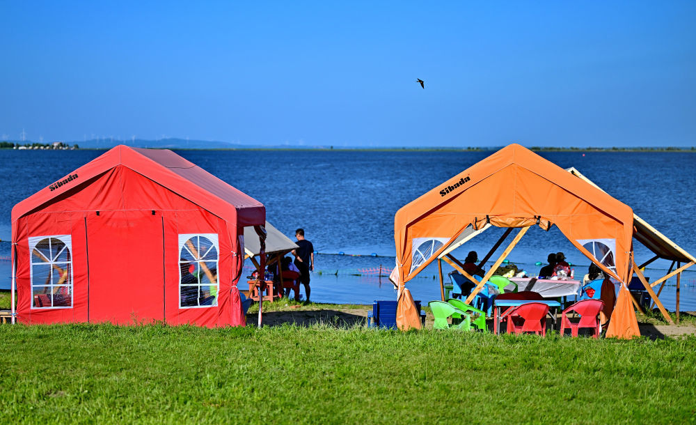人们在哈尔滨市松花江畔的帐篷中消暑休闲（7月6日摄，无人机照片）。新华社发（杨威摄）