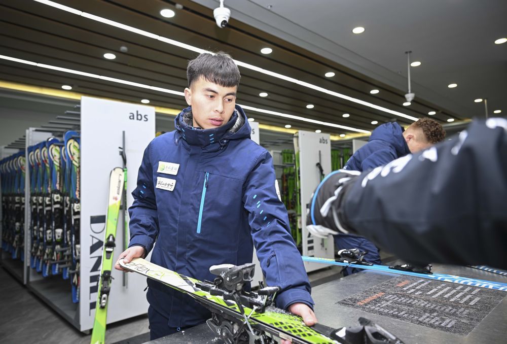 将军山国际滑雪度假区员工斯拉吉丁&middot;热依木为“雪友”整理滑雪板（1月24日摄）。他毕业后在这里工作已有四年。