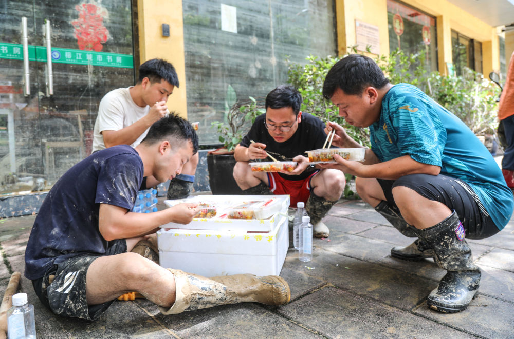 ↑6月27日,榕江县城,救援人员在救援间隙吃村民送过来的盒饭。