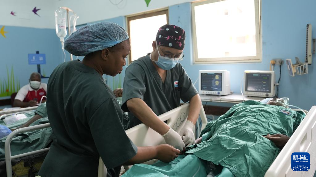 4月11日，在莫桑比克马普托，中国援莫医疗队医生凌勇（右）和当地医护人员对病人进行术后护理。新华社记者 刘杰 摄