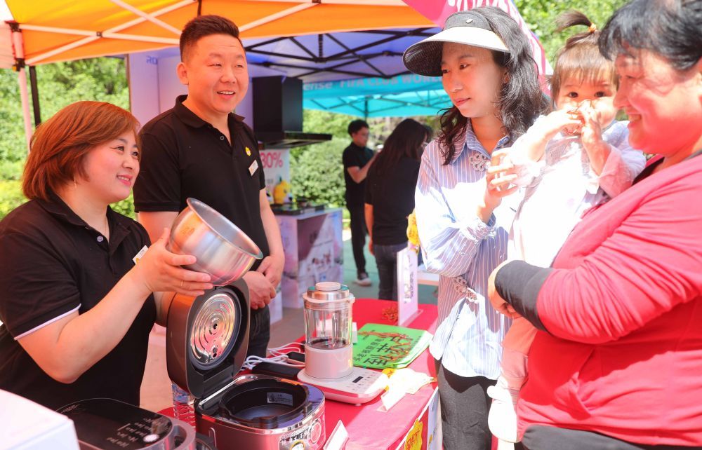 5月24日,在河北省秦皇岛市海港区白塔岭街道半岛书香社区开展的“消费品以旧换新进社区”活动中,商家为居民介绍家电产品及家电以旧换新补贴政策。曹建雄 摄