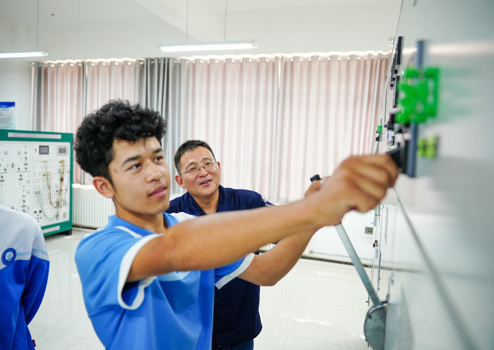 2025年6月27日，在新疆和田技师学院，北京援疆教师李东军（右）指导学生操作高压变配电设备。新华社记者 徐宏岩 摄