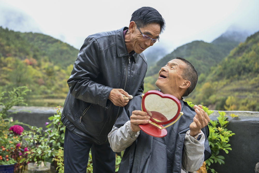 ↑村民桑建国（左）为秦海松理发后，二人相视而笑（2025年10月11日摄）。