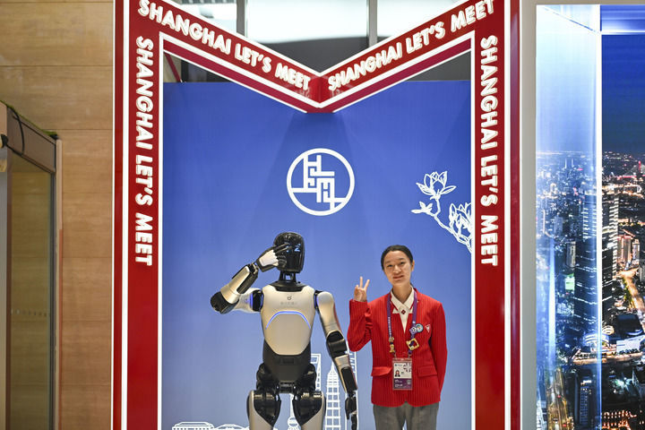 11月4日，志愿者（右）在第八届进博会新闻中心与“机器人志愿者”合影。新华社记者 陈浩明 摄