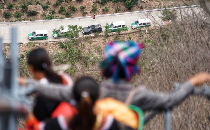 四川省昭觉县阿土列尔村（悬崖村旧称）村民沿着悬崖钢梯下山，准备搬家前往新家园，远处山脚下已停放好等待运送他们的车辆（2020年5月13日摄）。新华社记者 王曦 摄