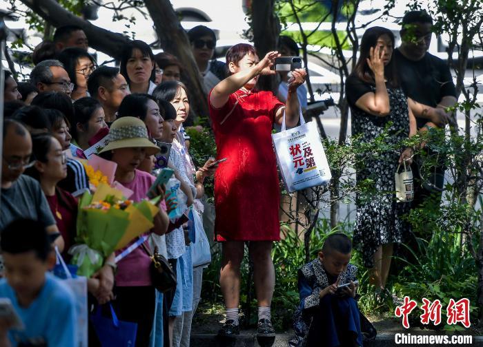 6月7日,新疆乌鲁木齐市,2025年普通高等学校招生全国统一考试乌鲁木齐考区第四中学考点,考生家长身穿红色旗袍在外等候。当日,2025年全国高考拉开帷幕。 中新社记者 刘新 摄