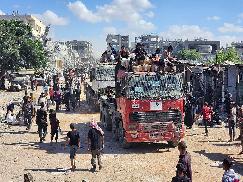 当地时间2025年10月12日,根据停火协议,载有人道主义援助物资和燃料的卡车通过凯雷姆沙洛姆口岸进入加沙地带,抵达汗尤尼斯。