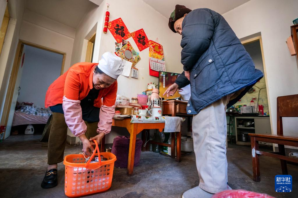 在昆明市幸福家园小区,王兰兰(左)给行动不便的老人送饭(2024年3月6日摄)。