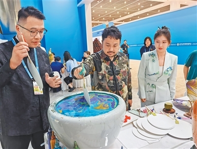 8月28日,外国嘉宾(中)在2025年上海合作组织峰会新闻中心体验非遗漆扇制作。 本报记者 黄发红摄