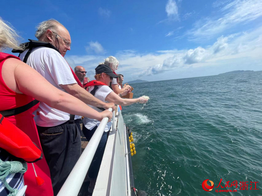 “里斯本丸”号船英军战俘后人将白色花瓣撒向蔚蓝的大海。人民网记者 王丽玮摄