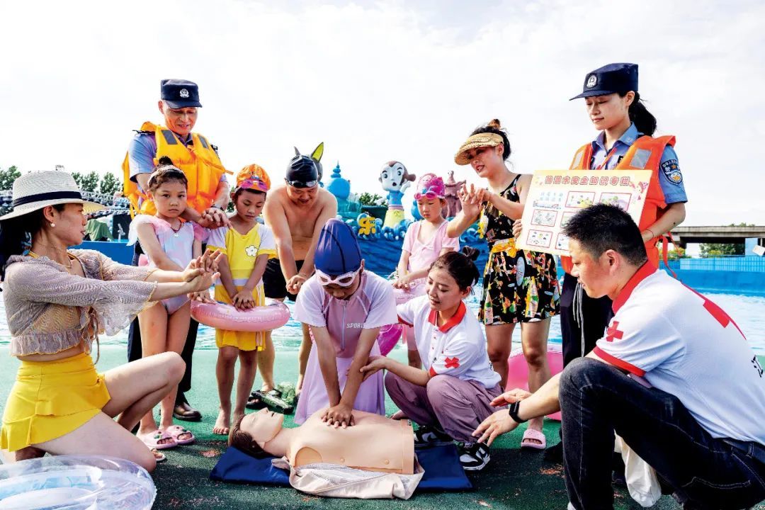 2024年7月7日，江苏泰州市一处水上乐园，红十字应急救援队志愿者利用仿真人模型向家长和儿童介绍心肺复苏法。图/视觉中国