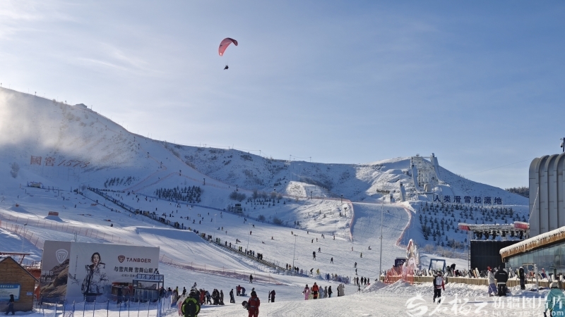 银雪之上，滑翔伞驭风漫舞、滑雪者踏雪飞驰，将军山国际滑雪度假区的冰雪天地满是热血与自由。石榴云/新疆日报记者 张婷摄