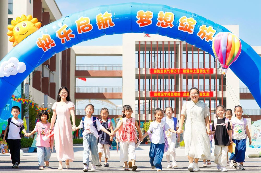 8月30日,在江苏省海安市南屏小学,一年级新生和老师一起走在校园里。新华社发(顾彬斌 摄)