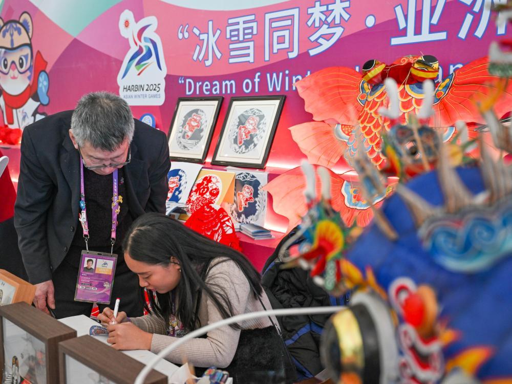 ↑在第九届亚冬会运动员村，菲律宾代表团的团部官员（右）在体验非遗龙头蜈蚣风筝制作技艺。新华社记者 王曦 摄