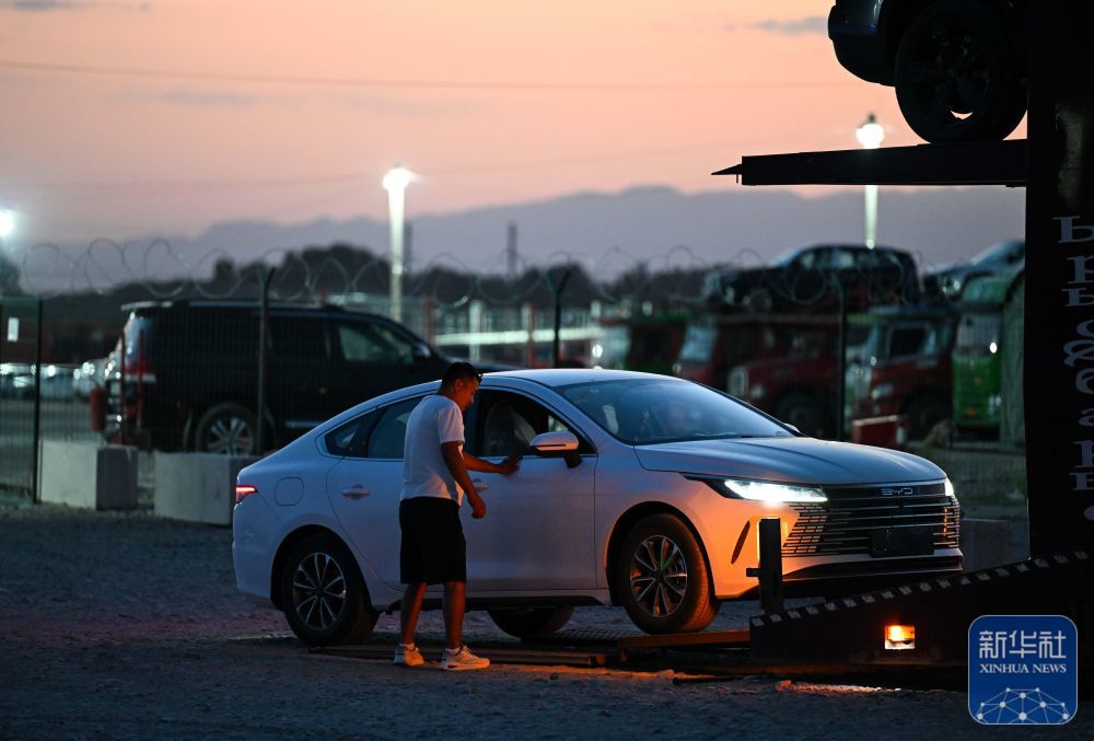 在哈萨克斯坦扎尔肯特的中转停车场,当地运输公司工作人员装载从中国进口的汽车(5月23日摄)。进口自中国的汽车将从这里启程,运往中亚、欧洲各地。