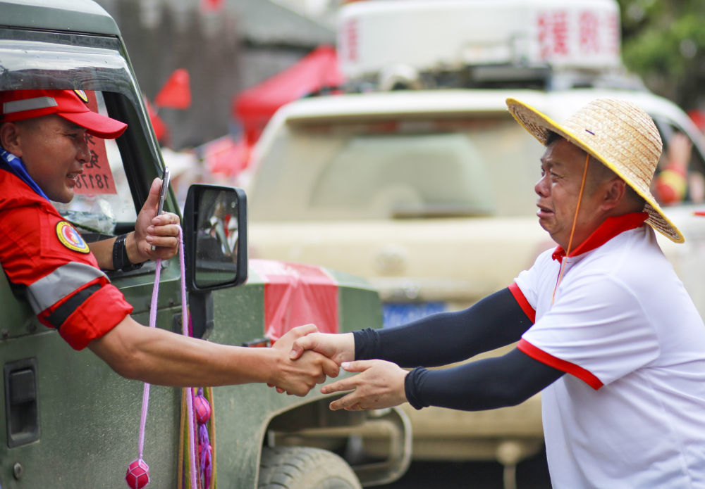 2025年7月3日,在贵州省榕江县,一名救援队员在撤离时与当地居民握手道别。新华社发(龙顺伟摄)