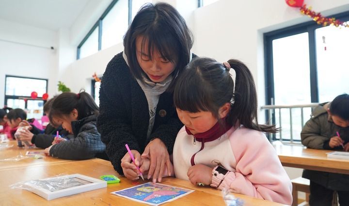 2月21日，重庆市丰都县包鸾镇“鸾妈妈”青少年家庭教育互助会志愿者在辅导孩子制作钻石画。丰都县委宣传部提供。