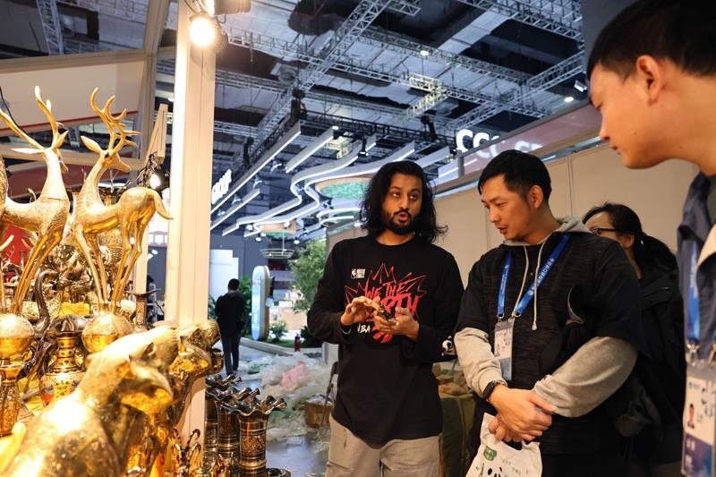 △一名巴基斯坦展商（左）在布置进博会展位时与工作人员交流。