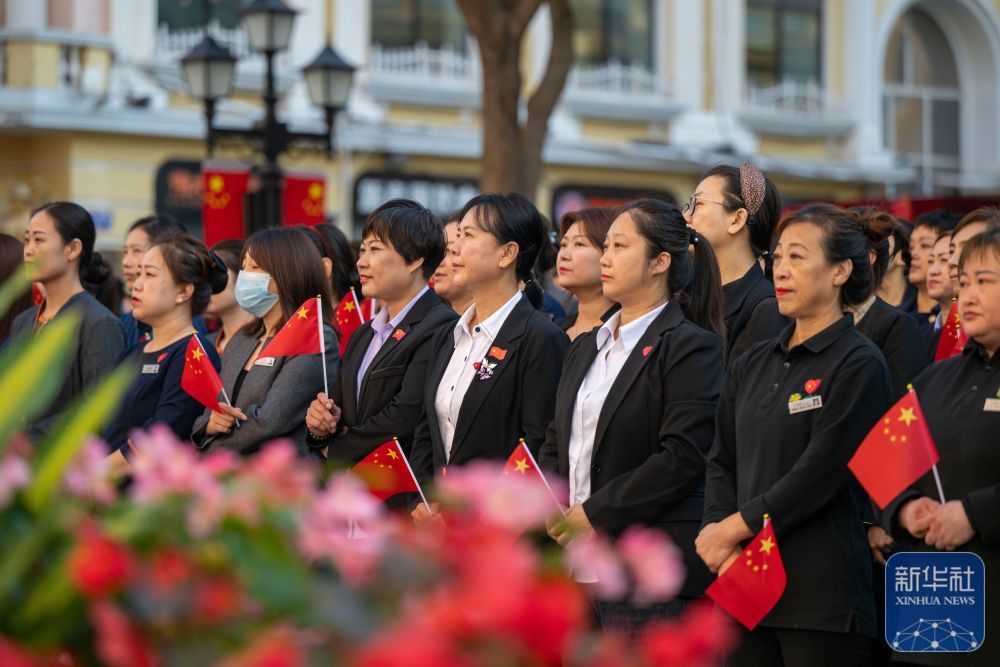 ↑ 10月1日,人们在哈尔滨市道里区中央大街参加升旗仪式。新华社记者 张涛 摄