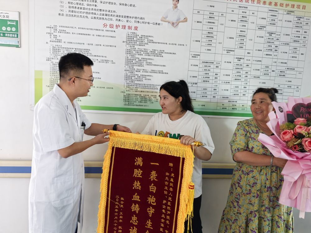 6月27日，在麦盖提县人民医院，患者热合曼·艾买尔的亲属将一面锦旗和一束鲜花送到了日照援疆医生魏鑫的手中。（新华社记者 顾煜 摄）