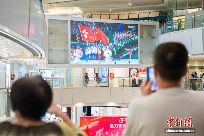 11月9日晚，香港市民在觀塘的一家商場內通過大螢幕觀看在廣州舉行的第十五屆全國運動會開幕式。圖為大螢幕顯示出粵港澳三地運動員代表團一同入場。　中新社記者 侯宇 攝