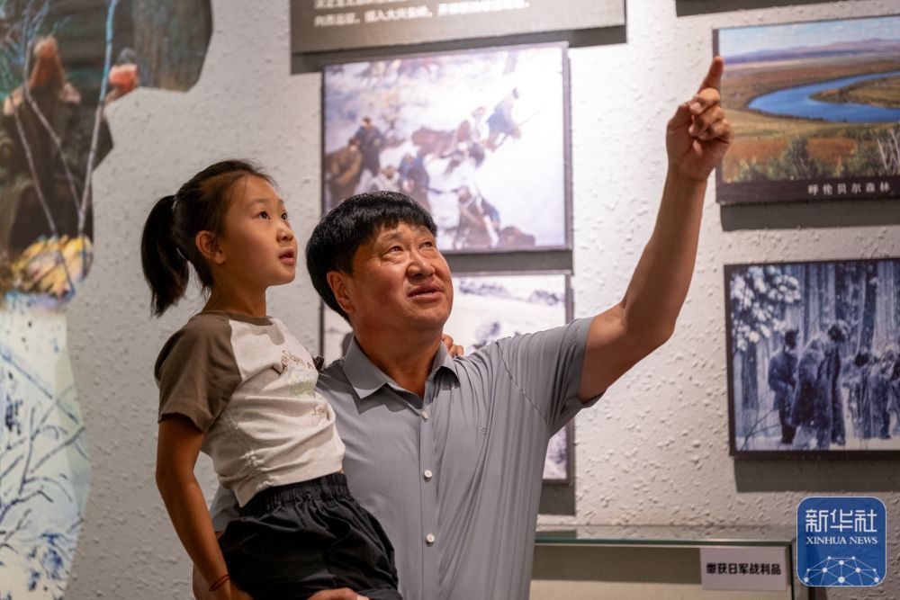 ↑8月23日,内蒙古呼伦贝尔市阿荣旗,孙福贵在呼伦贝尔东北抗联纪念馆向孙女讲述东北抗联在呼伦贝尔地区进行敌后游击的事迹。新华社记者 马金瑞 摄