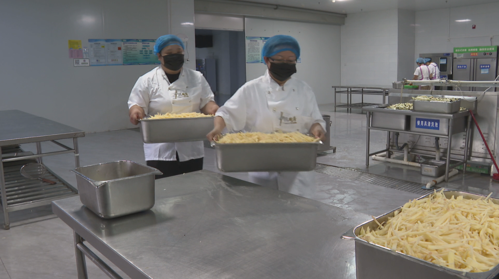 在河南省鹤壁市外国语中学后厨,学校组建的专业餐饮团队正在配餐。(霍丹 摄)