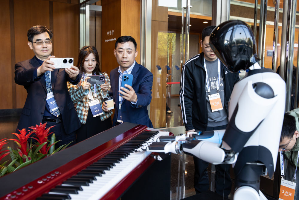 在南京举行的2025产业科技创新与投资促进大会展示区，嘉宾在拍摄机器人弹钢琴（2025年3月26日摄）。新华社发（张梦 摄）